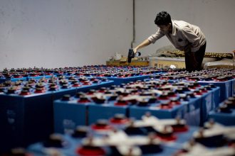 Profissional verifica um conjunto de baterias industriais dentro de uma instalação de armazenamento de energia.