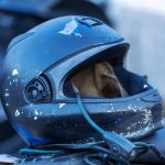 Close-up de um capacete de motocicleta com marcas de uso e riscos na superfície.