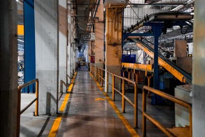Interior amplo de uma fábrica moderna, com máquinas industriais e sistemas de esteiras transportadoras