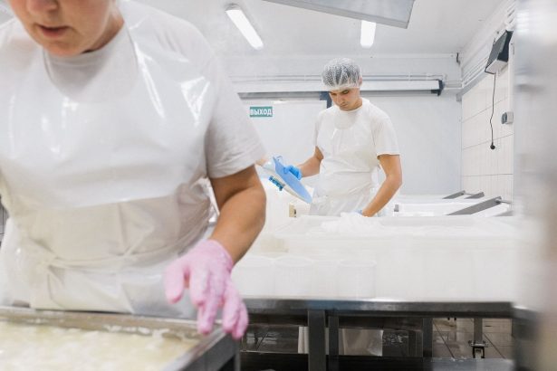 Trabalhadores usando equipamentos de proteção processam produtos em uma fábrica de alimentos.