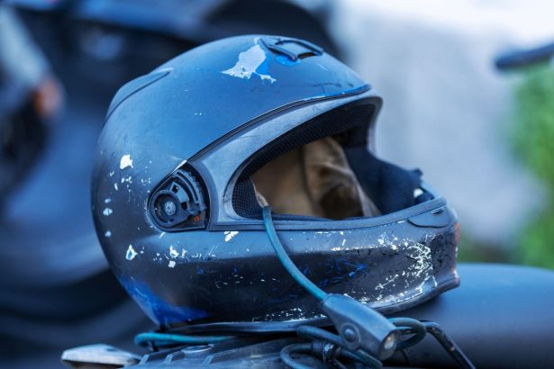 Close-up de um capacete de motocicleta com marcas de uso e riscos na superfície.
